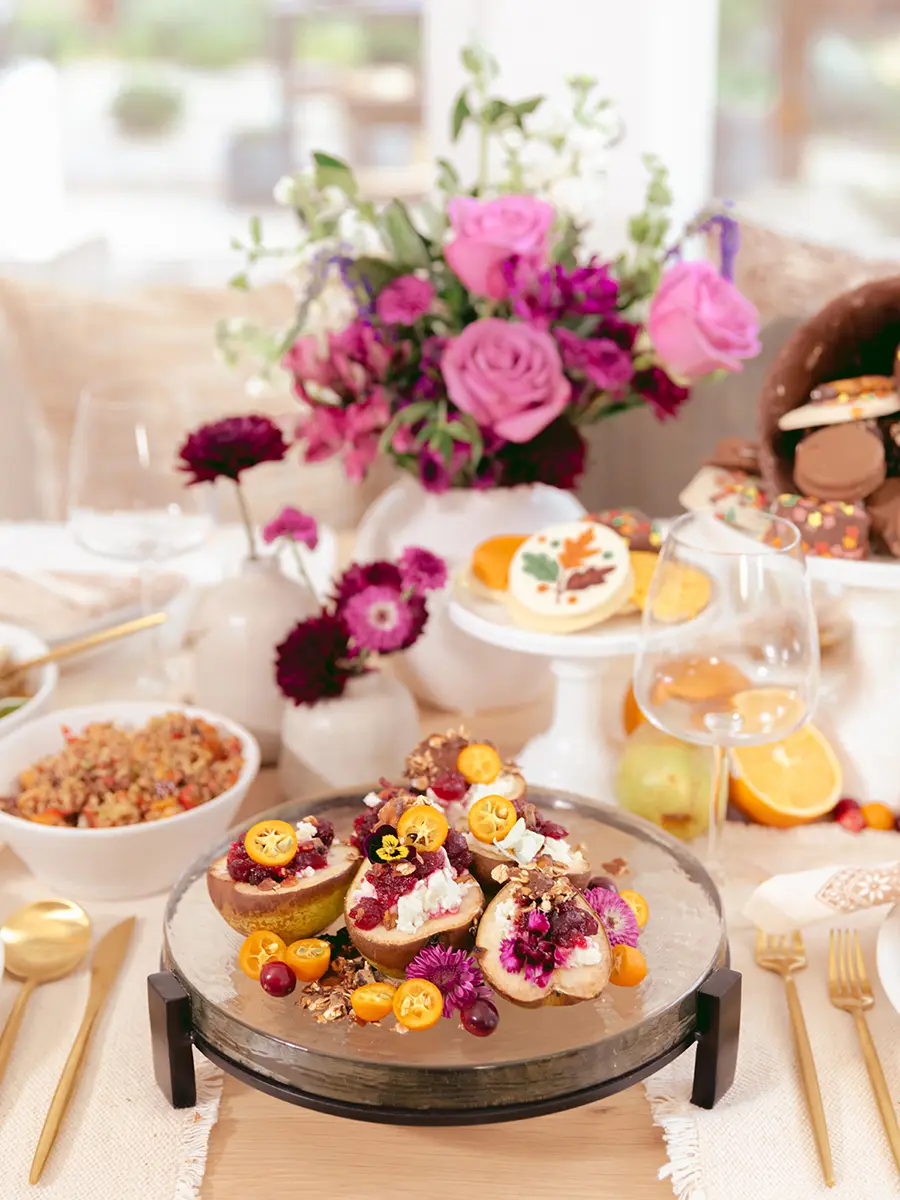 Thanksgiving potluck table laid with food, dessert and flowers.