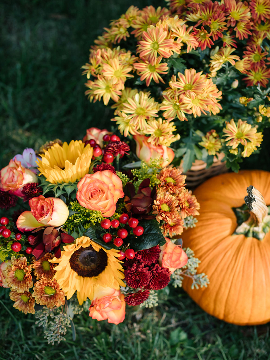 What is Friendsgiving with two bouquets of flowers next to a pumpkin.