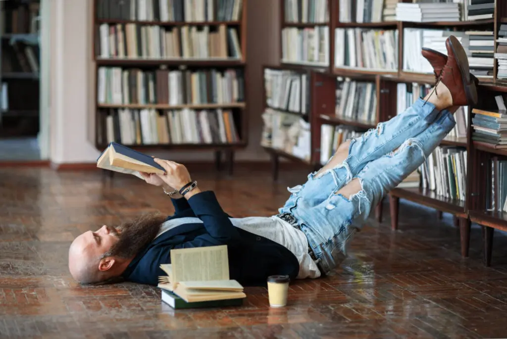 new years resolutions bearded hipster man relax and reading book lies on the floor in library