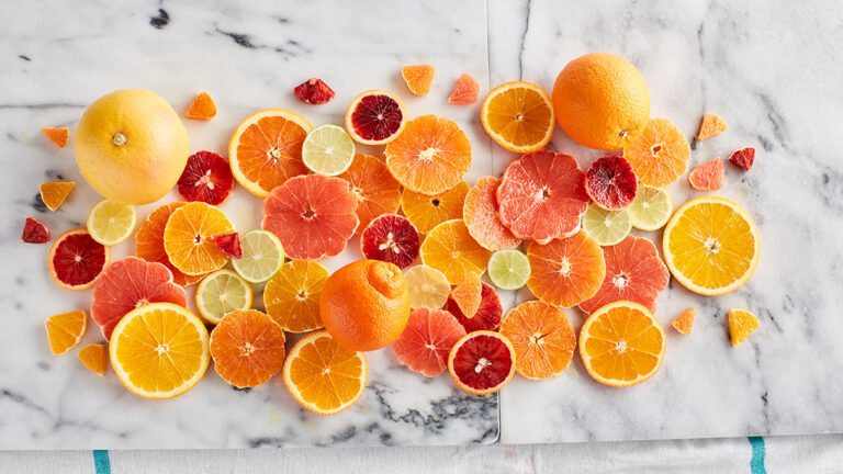 Guide to oranges sliced and displayed on a marble counter top.