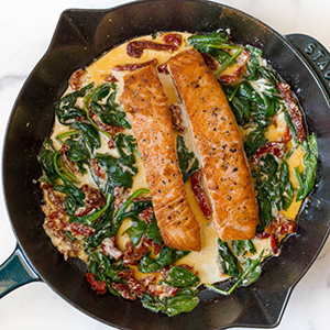 Romantic dinner ideas with cooked salmon and cream sauce inside a cast-iron skillet.
