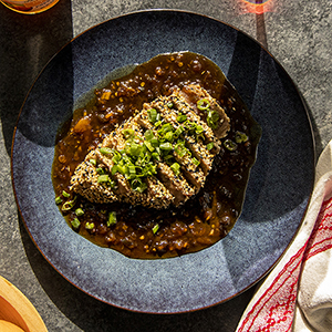 Romantic dinner ideas with a plate of sliced and seasoned tuna steak on top of sauce.