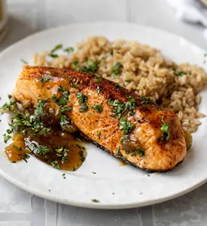 Salmon recipes with a piece of grilled salmon on a plate with brown rice.