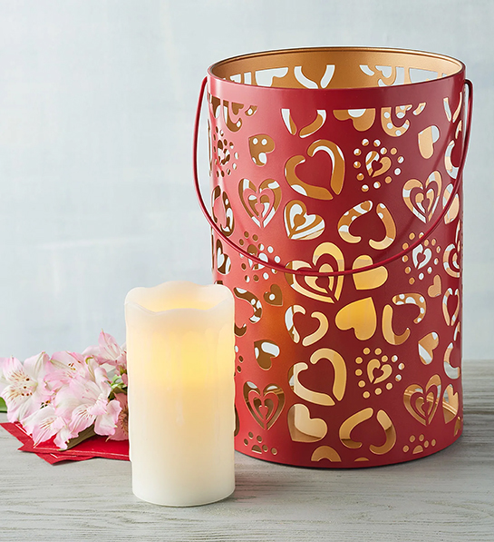 Valentine's Day gifts for her with a red tin lantern with cutout hearts next to an electric candle.