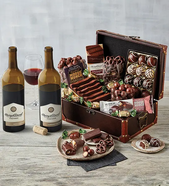 Valentine's Day gift ideas for him with a chest of chocolate goodies next to two bottles of wine.