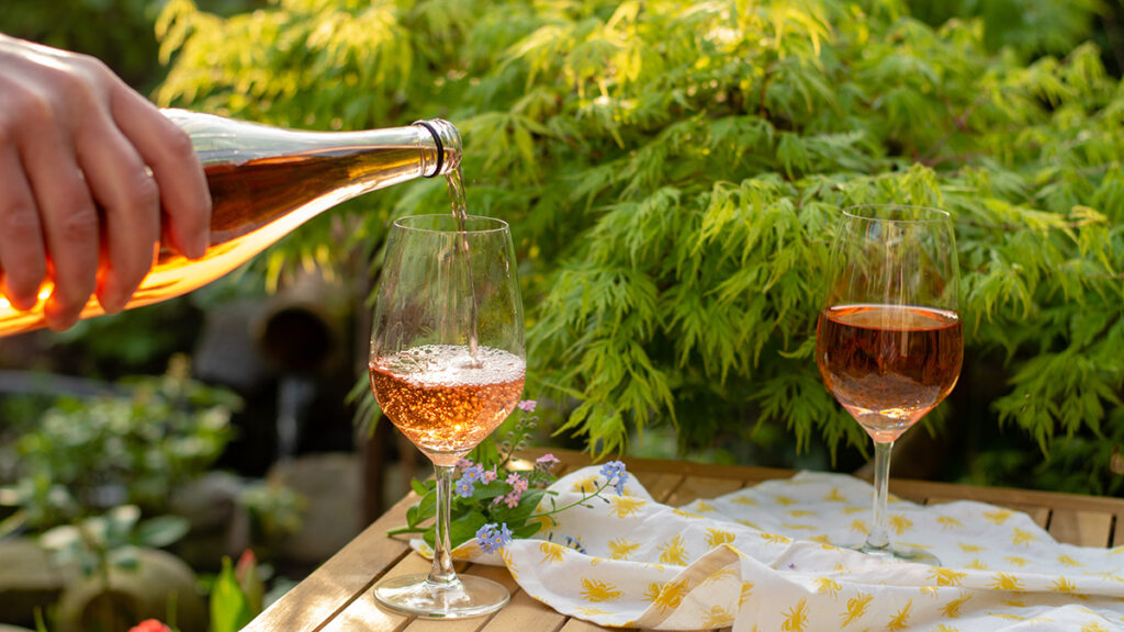 Wine trends with a hand pouring a glass of orange wine outside.