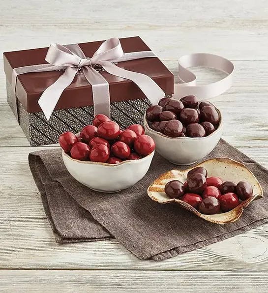 Easter basket stuffers with a gift box next to several bowls of chocolate covered cherries.