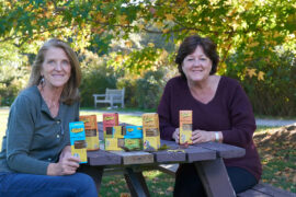 Effie's Homemade Oatcake Biscuits founders sitting on a picnic bench with boxes of cookies.
