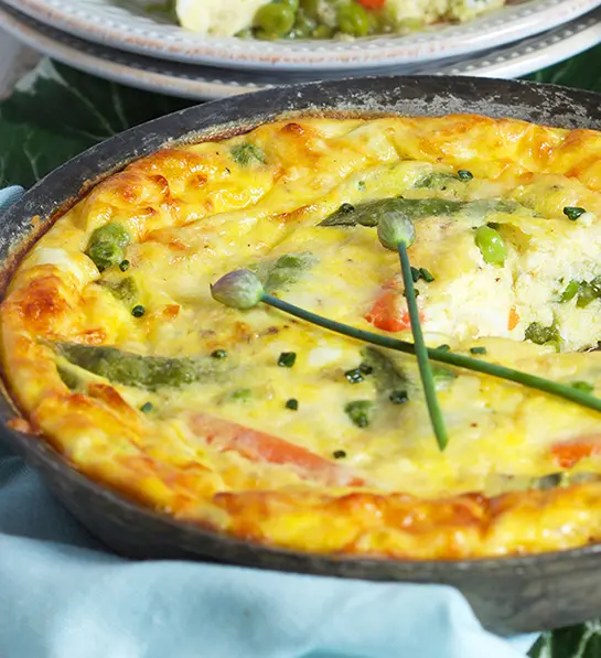St. Patrick's Day food with a cheesy snap pea and bacon frittata in a cast-iron skillet.