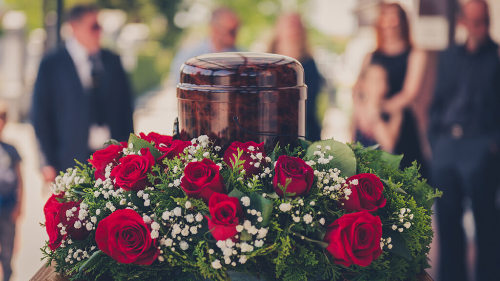 Cremation service with a wreath of flowers around an urn.
