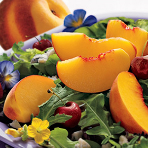 Mesclun salad with sliced peaches on top.
