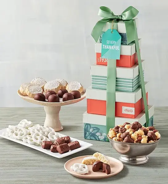 Unique thank you gifts with a tower of gift boxes next to an array of chocolates, cookies, and Moose Munch.