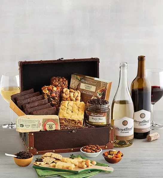 Unique thank you gifts with a chest of sweet and savory treats next to two bottles of wine.