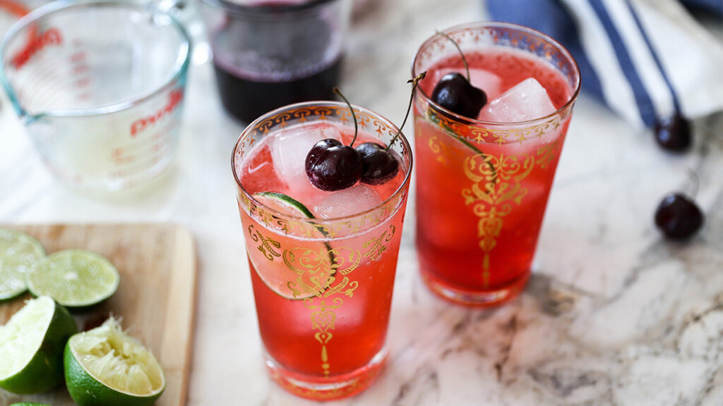 Cherry recipes with two glasses of cherry limeade topped with cherries.