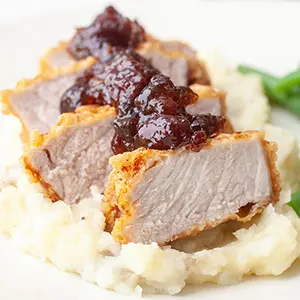 Cherry recipes with slices of fried pork on mashed potatoes topped with cherry chutney.