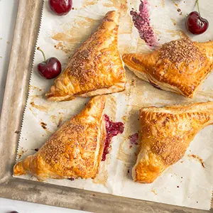 Cherry recipes with four cherry turnovers on a cooking sheet.