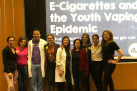 Dina Colombo with group of people standing in front of a projection about e-cigarettes.