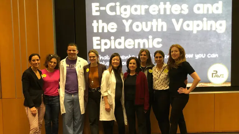 Dina Colombo with group of people standing in front of a projection about e-cigarettes.