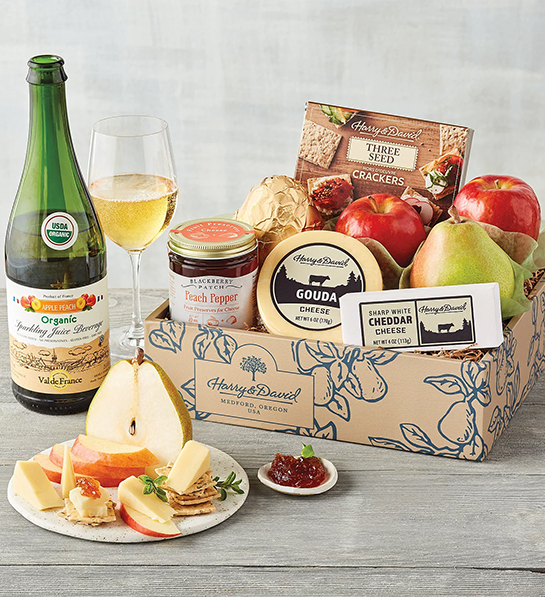 Fruit and cheese pairings with a box of cheese, fruit and crackers next to a bottle of sparkling juice.