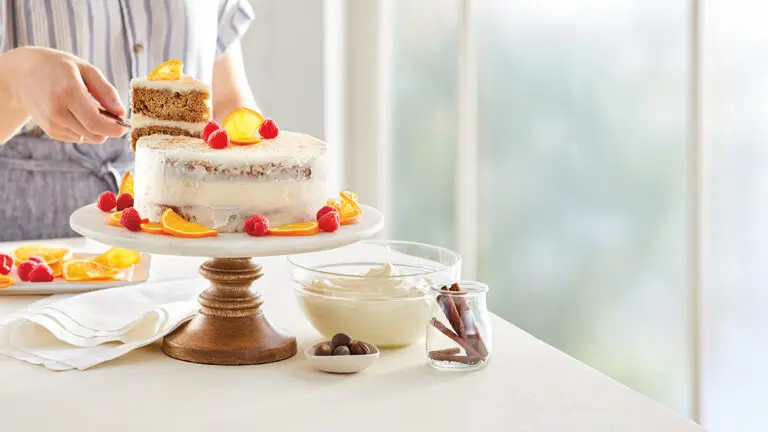 Gluten-free cakes with a cake on a stand with someone slicing a piece.