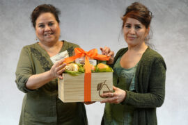 Packing baskets with two women holding a Harry & David basket smiling at the camera.