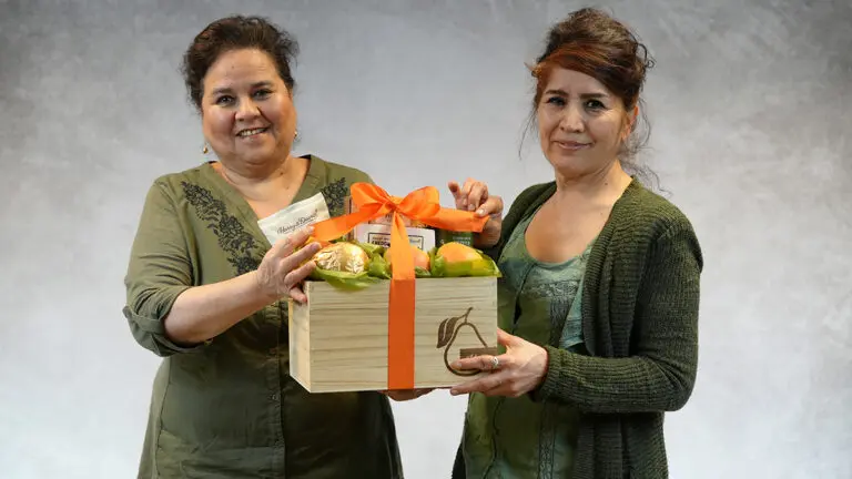 Packing baskets with two women holding a Harry & David basket smiling at the camera.