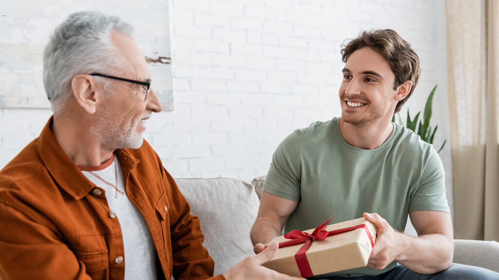 happy man congratulating dad on fathers day and giving him gift