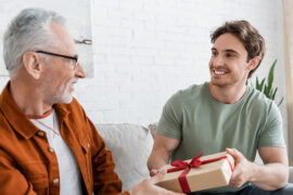 happy man congratulating dad on fathers day and giving him gift