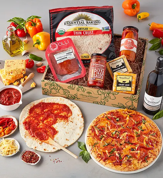 Father-in-law gifts with a pizza making kit in a box surrounded by ingredients for making pizza.