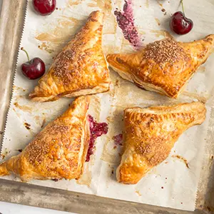 Cherry turnovers on a baking sheet.