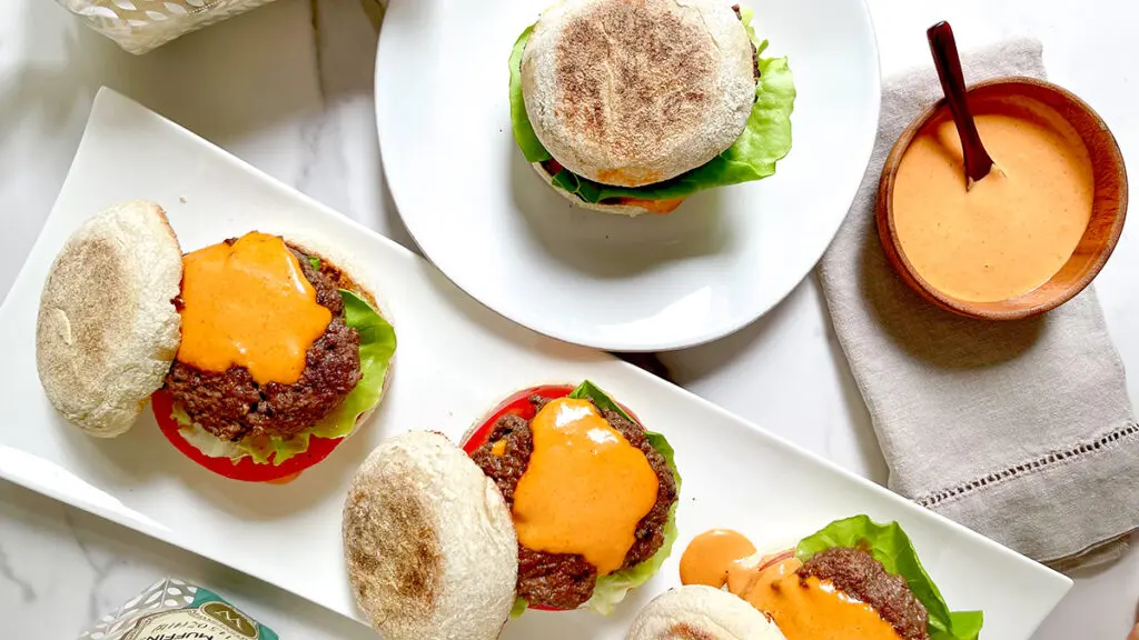 Gourmet burgers with Wolferman's English muffins on a serving tray.