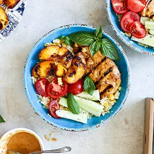 Bowl of grilled peaches, chicken, rice, and other veg.
