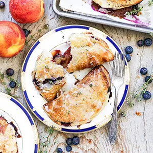 Peach recipes with peach and blueberry hand pies on a plate.