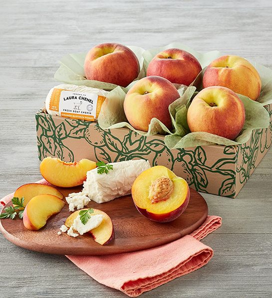Types of peaches in a box with a plate of sliced peaches and chevre.