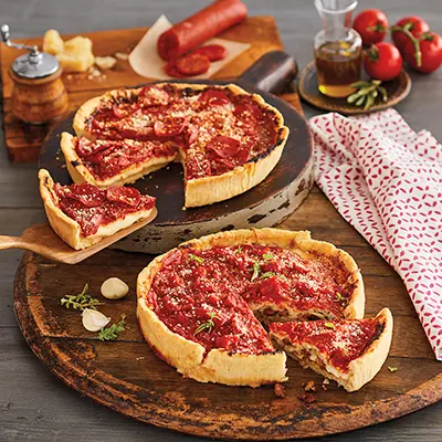 Types of pizza with two pizza pies on a counter.