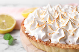 Serving board with delicious lemon meringue pie on white marble