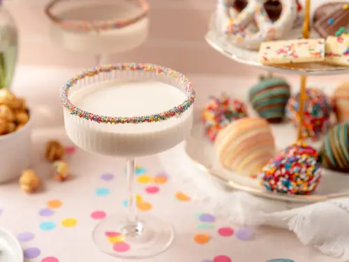Birthday cake martini surrounded by chocolate covered strawberries and other treats.