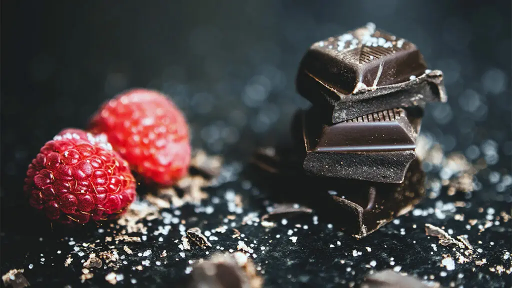 Flavor pairings with several raspberries next to a stack of dark chocolate.