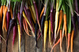 Multi-colored carrots on a wood table.
