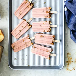 Plum nectarine popsicles on a baking sheet.