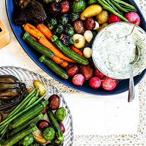 Roasted carrots and other vegetables with a bowl of yogurt dip.