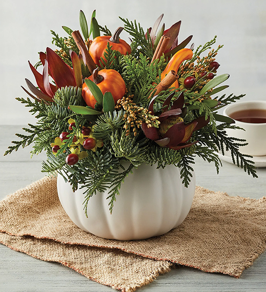 Fall gifts with a bouquet of greenery, fall leaves, and tiny pumpkins in a pumpkin shaped vase.