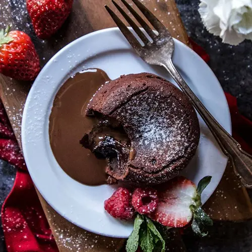 Types of cake with a lava cake on a plate with sliced strawberries.