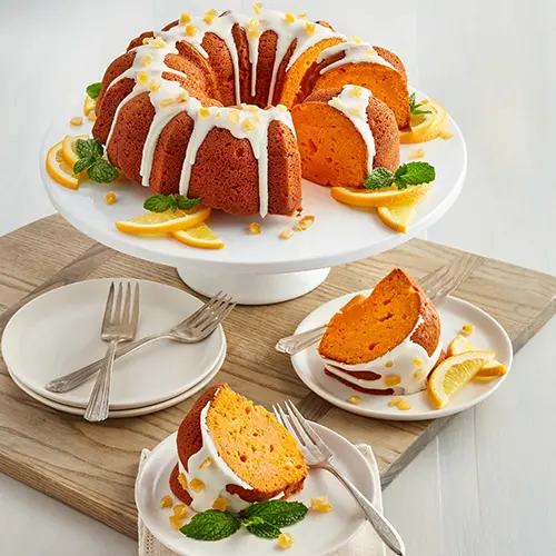 Types of cake with a lemon bundt cake on a platter with two plates holding slices of cake.