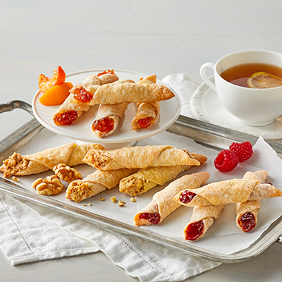 Types of pastries with a platter of kiffles next to a cup of coffee.
