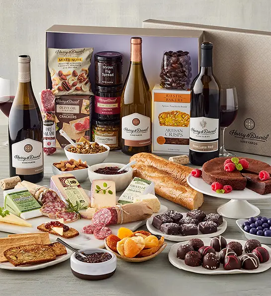 Ultimate wine pairing cheese gift with bottles of wine, types of cheese, sweet and savory snacks.