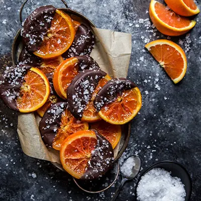 Sliced Cara Cara oranges dipped in chocolate and sprinkled with salt.