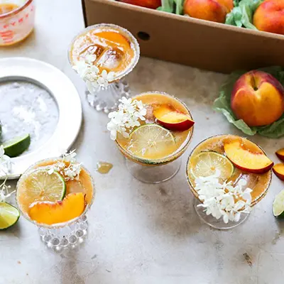 Peach margaritas with elderflower garnish.