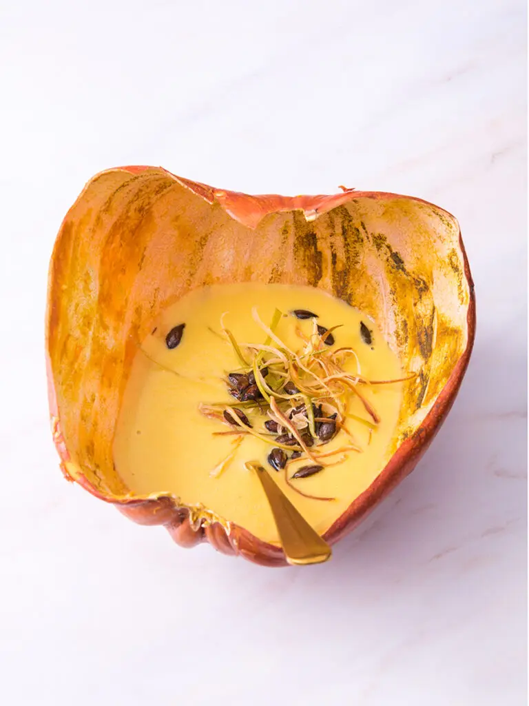Regenerative farmed pumpkin soup in its own skin topped with pumpkin seeds.