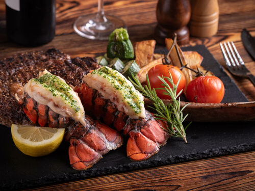 surf and turf photo of two lobster tails and filet mignon.